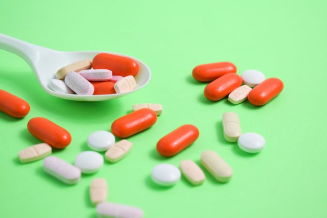 Variety of pills with plastic spoon on green table