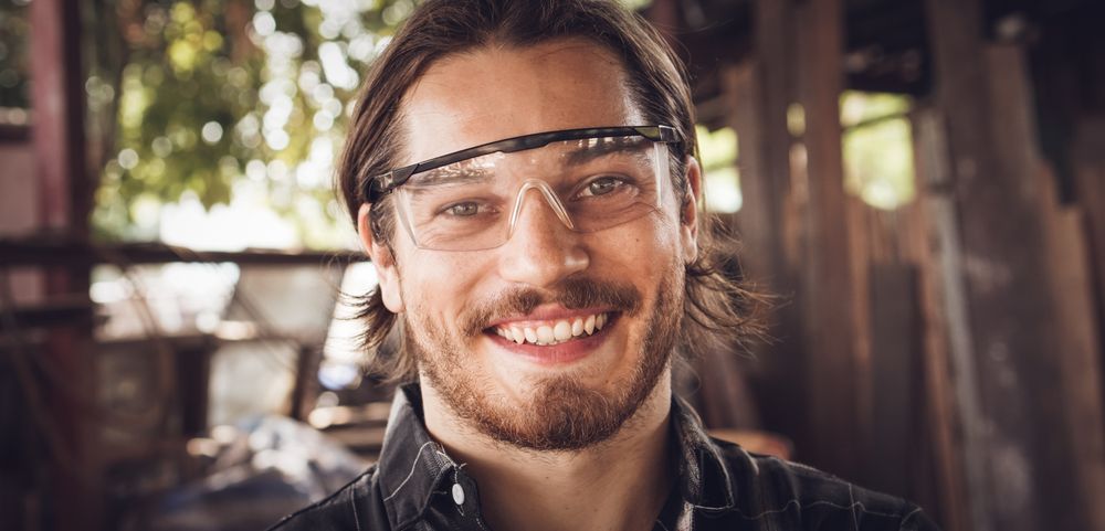Smiling face of male carpenter looking at camera at the workshop