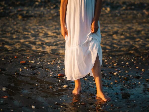 Adorable girl walking on seaside at sunset