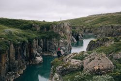 Woman standing on edge of cliffs over water