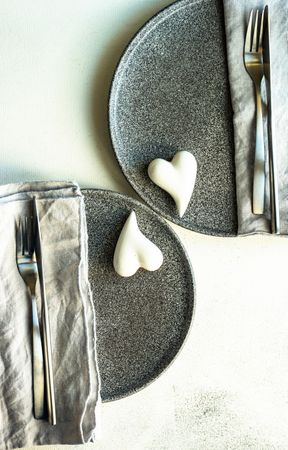 Top view of grey plates and hearts for romantic dinner