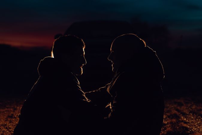 Men hugging and sitting on ground on field at night