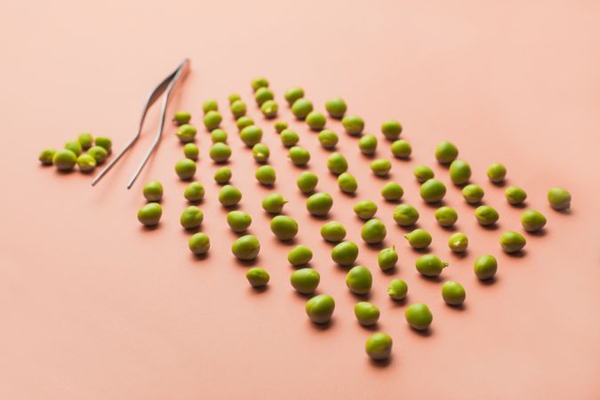 Set of peas placed orderly on salmon colored background