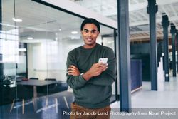 Creative young businessman holding a smartphone in a modern office bxVyZ5