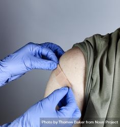 Vaccine shot being bandaged by hands in latex gloves 5wB310