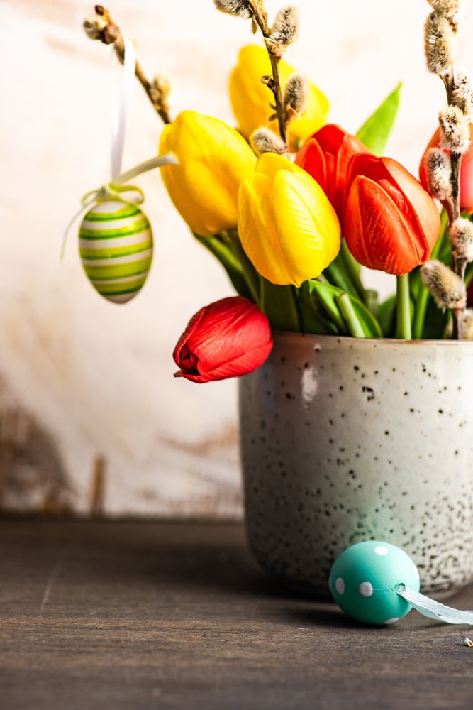 Easter card concept with egg decorations around vase of tulip