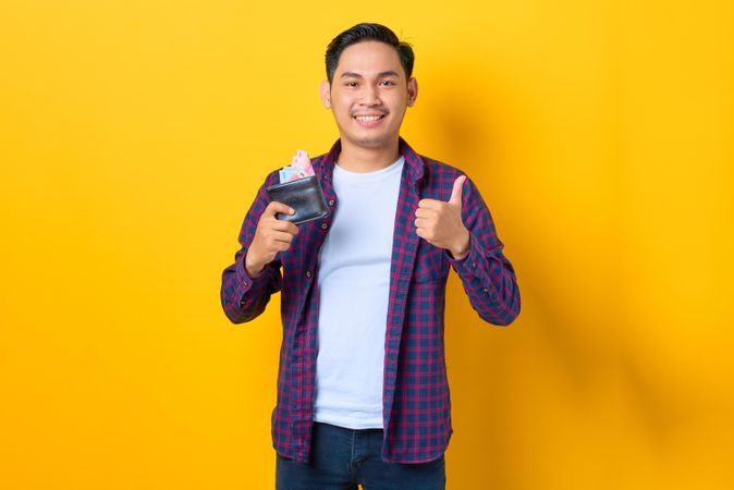 Man with thumbs up holding wallet with cash