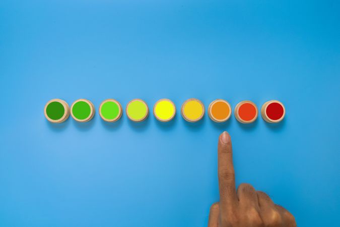 male hand point risk level meter indicator from low to high on wooden blocks. isolated on blue background. concept of risk management
