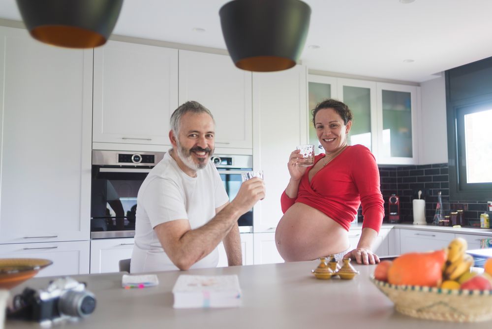 Smiling expecting woman and husband in bright kitchen