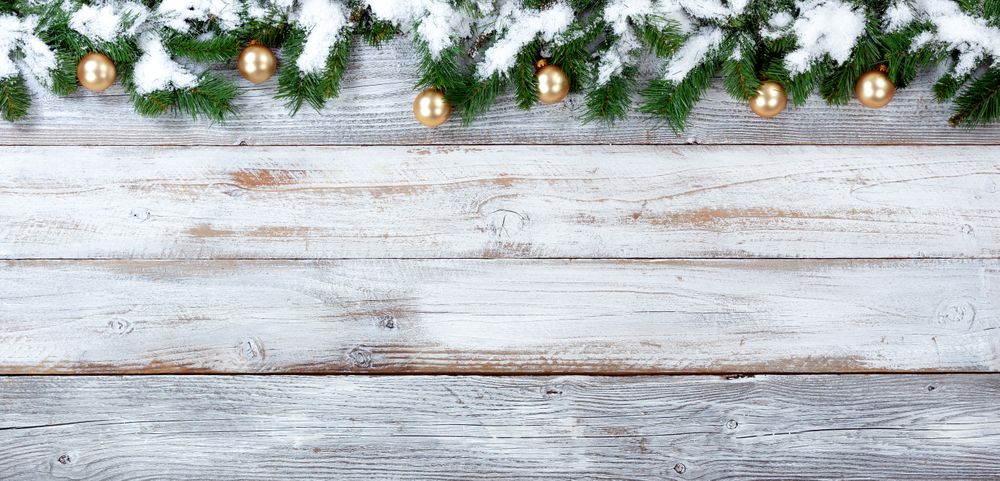 Snowy Christmas evergreen branches and golden ornaments on vintage wooden planks