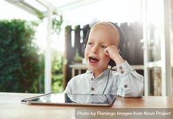 Happy blond boy using headphones listening to something on digital tablet 5wWOZ5
