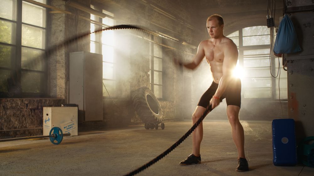 Strong Muscular Shirtless Sportsman Works out Hard with Battle Ropes as Part of His Cross Fitness Training Routine.