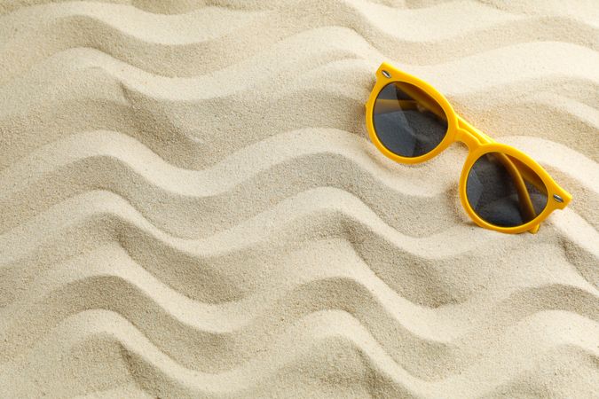 Clear sea sand with sunglasses, space for text. Summer vacation background