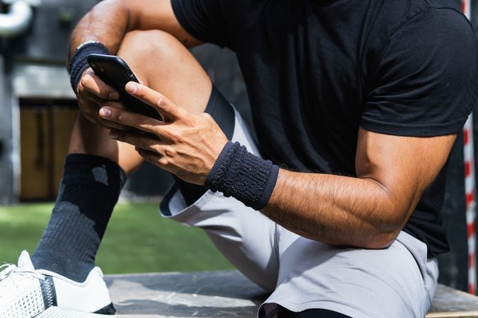 Anonymous fit man browsing smartphone during training