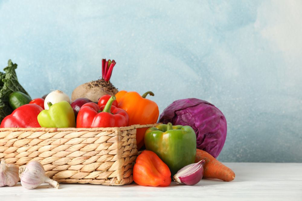 Wicker basket and vegetables on wooden background, copy space