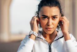 Serious woman adjusting her earbuds