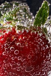Ripe strawberry with bubbles in water