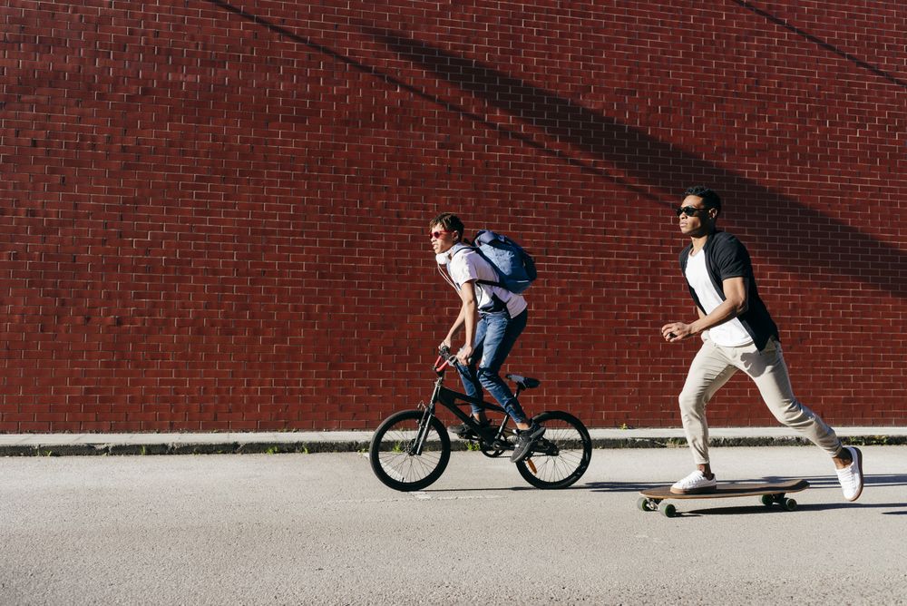Young Black men riding bicycle and skateboard