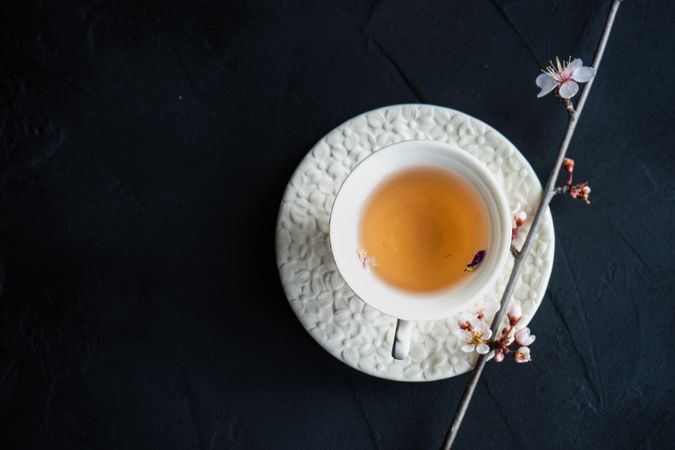 Top view of cup and saucer of tea and pink blooming tree