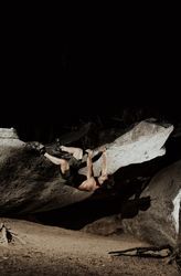 Man practicing rock climbing among large rocks in a forest