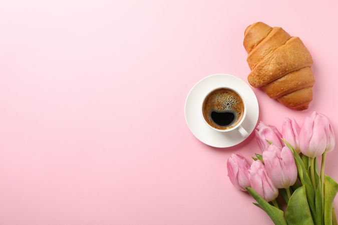 Tulips, croissant and cup of coffee on pink background, top view with copy space