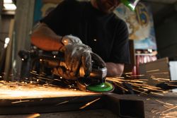 Male worker using electric grinder in workshop