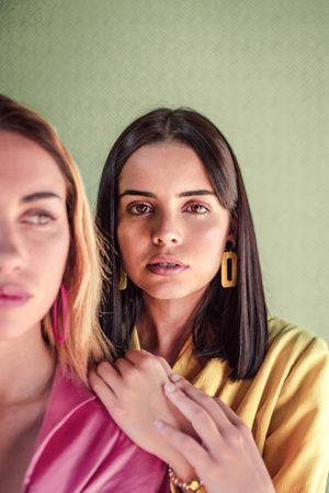 Young trendy women in bright clothes looking at camera