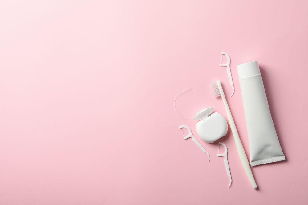 Tools for dental care on pink background, space for text