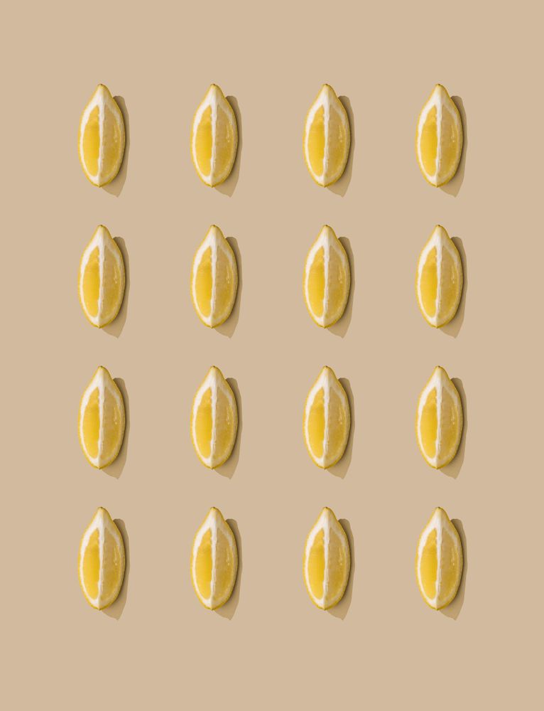 Pattern of lemon fruit slices and pastel sand background