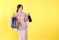 Cheerful Indonesian Asian Woman Wearing Kebaya, Holding Various Colors of Paper Bag.