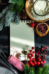 Notebook on kitchen table surrounded by baking ingredients and Christmas decorations