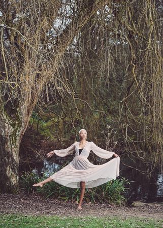 Woman in ballerina pose under tree