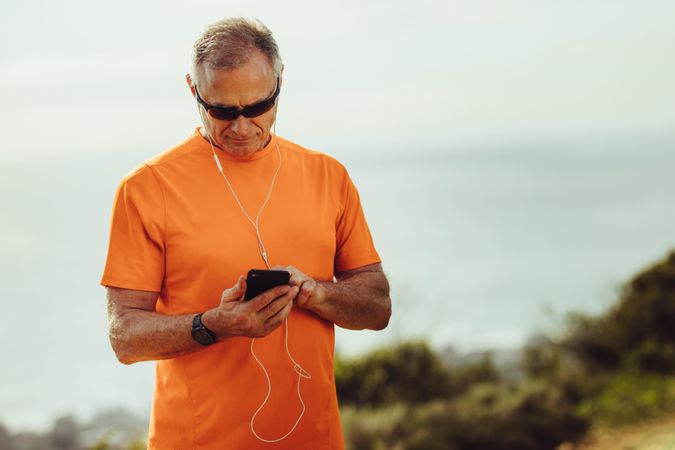 Fitness man playing music on mobile phone during workout