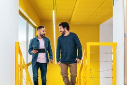 Two male coworkers working and talking in a coworking