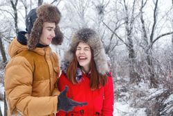 Teenage couple laughing in wintery forest