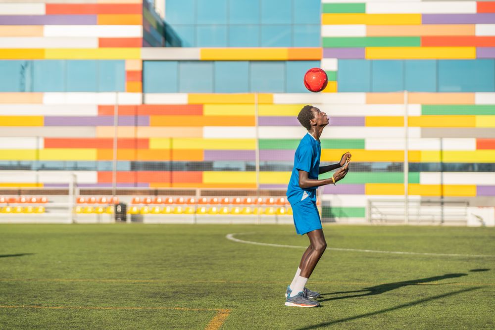 Black teenager jugging football ball on head