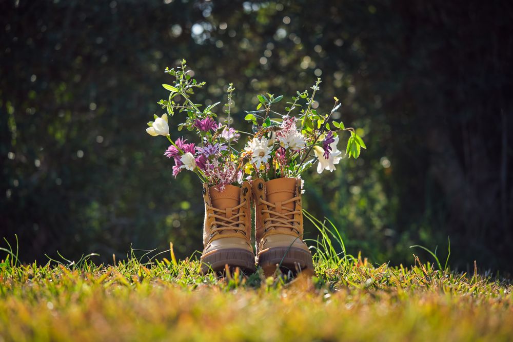 Bright flowers in boots on grassy terrain