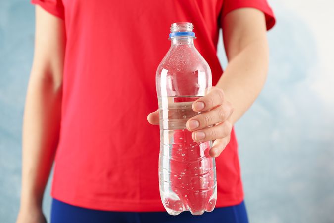 Person holding out plastic water bottle