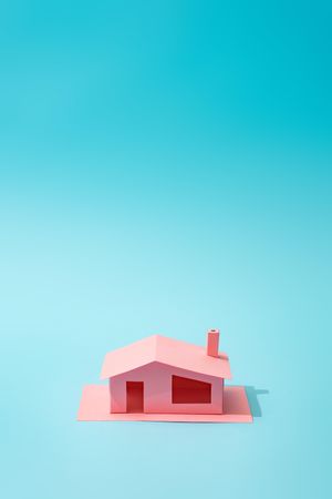 Pink paper house on blue background