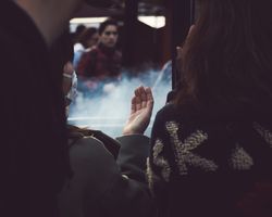 Tokyo, Japan - November 19th, 2019: Young woman holds hand up with smoke in the background