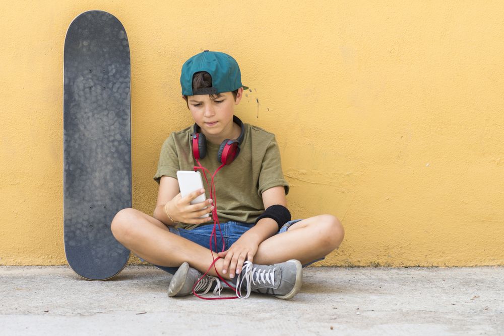 Portrait of a teenager sitting on the floor on a street road texting
