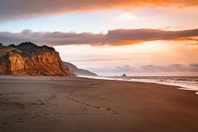 Footprints on a quiet beach with cliffs later afternoon
