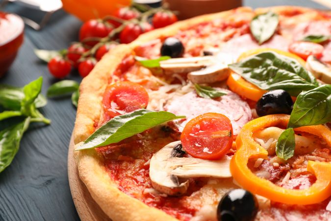 Delicious pizza and ingredients on wooden background, close up