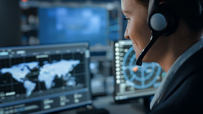 Cybersecurity Analyst Monitors Global Network Activity. Focused on Digital Screens Displaying World Map and Data Charts.