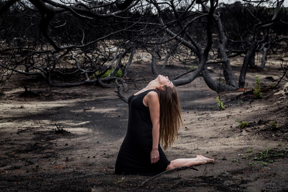 Woman posing on ground near dry trees