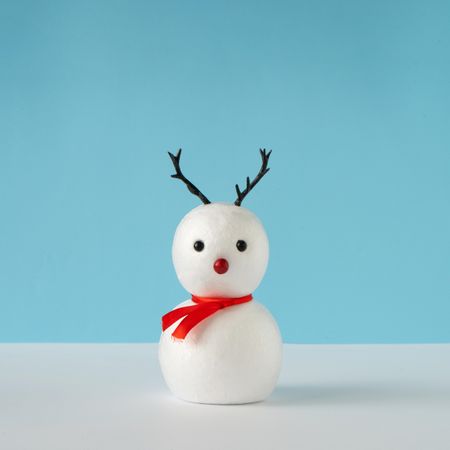 Snowman on bright blue background with reindeer nose and antlers