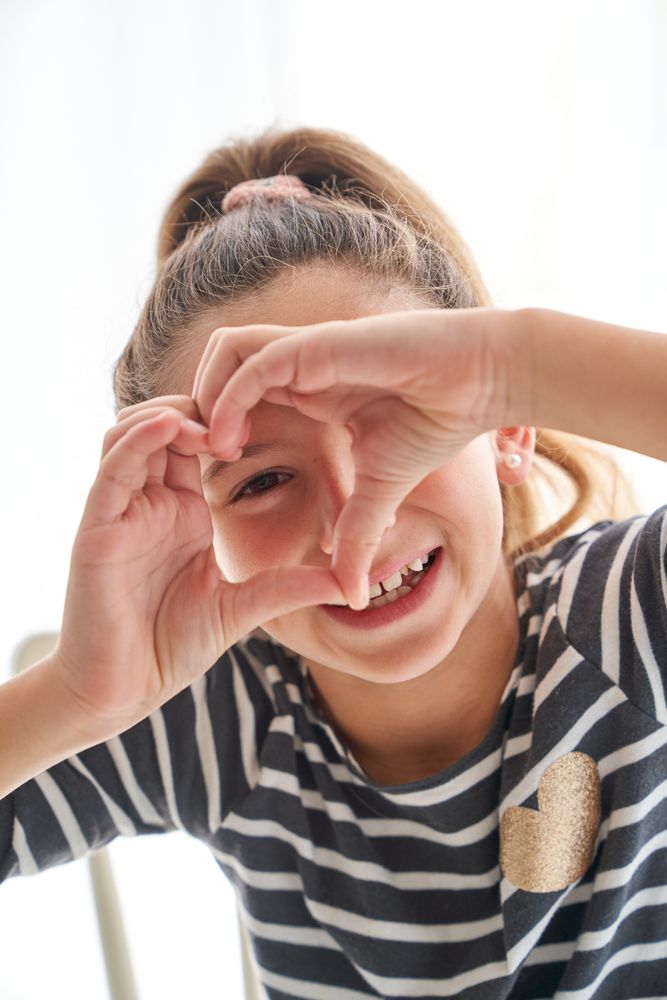 Funny girl making heart gesture
