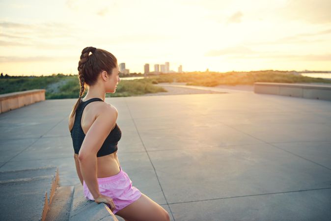 Fit woman resting on concrete wall between exercises