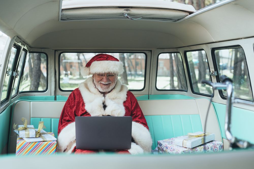 Santa Claus working at laptop in van