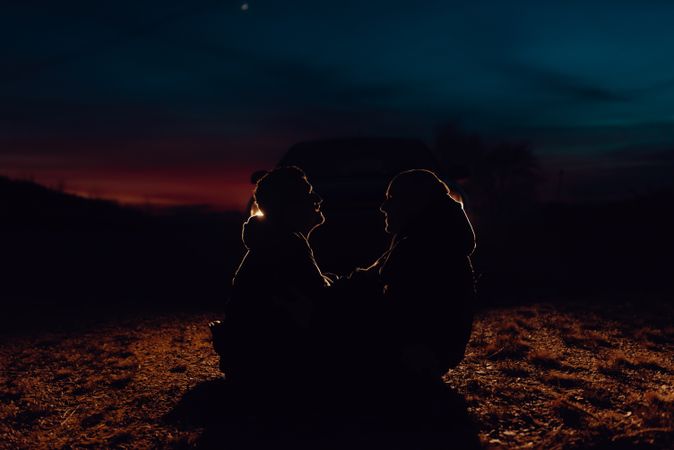 Men hugging and sitting on ground on field at night